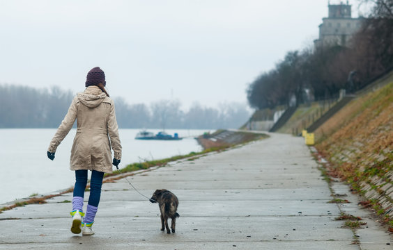 Teenage girl walking dog on cloudy autumn day.