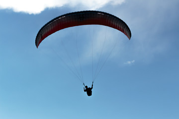 Parachute and human silhouette. Blue sky and adventure.