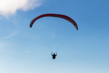 Parachute and human silhouette. Blue sky and adventure.