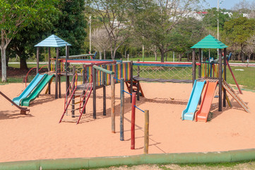 Playground for kids with many slides, swings, toys for play. The playground is made of wood toys and a sand floor.