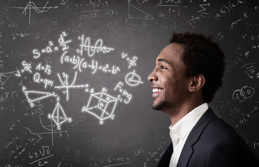 African American guy and formulas on chalkboard