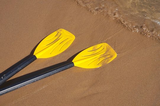 Yellow oars on sandy beach with motion blur from waves