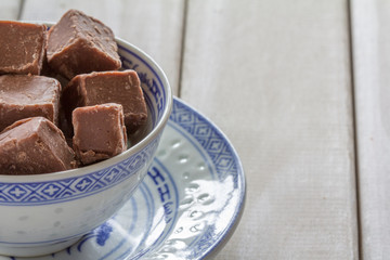 Chocolate Fudge in a Bowl on White Wooden Table with Copy Space Right