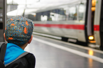 the back of a boy waits train on railway platform