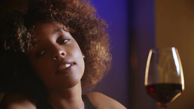 Close up beautiful sexy young black fancy woman boring and drinking red wine in bar