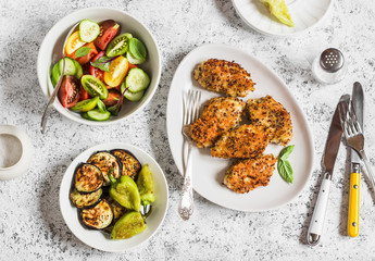 Quinoa crusted chicken, vegetable salad, grill eggplant and pepper - dinner table. On a light background, top view