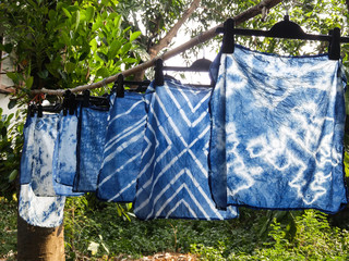 Beautiful natural indigo tie dye fabric with garden view in background.