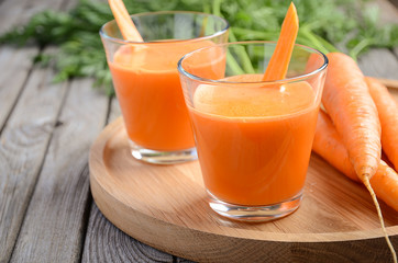 Fresh carrot juice on wooden background, selective focus, copy space