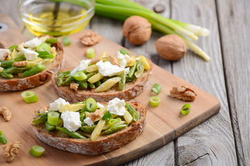 Bruschetta with French beans, green onions, feta cheese and walnuts, selective focus
