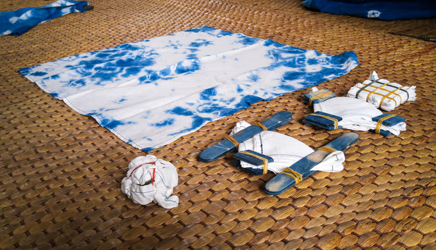 Natural indigo tie dye equipment on rattan mat.