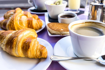 Breakfast with coffee and croissants on table