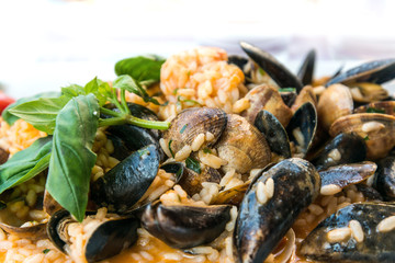 Tasty risotto with Mussels, fresh herbs vegetables on a white pl