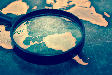 Magnifying lens on grunge world map