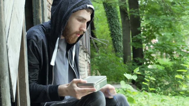 Man feels nervous while checking his drugs next to the abandoned building
