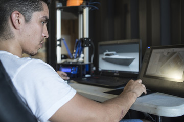 Designer using computer app while working with 3D printer