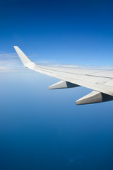 Airplane wing during flight over the blue sky