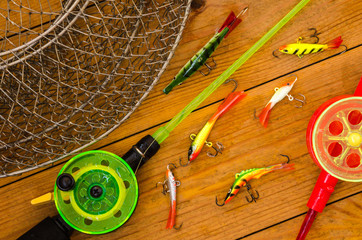 Fishing accessories for winter. Tackles, bait, lure, jig, hook, net. Wooden background. Outdoor activity and leisure concept.  © polina_petrenko