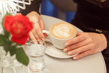 Close-up female hands holding cup with coffee