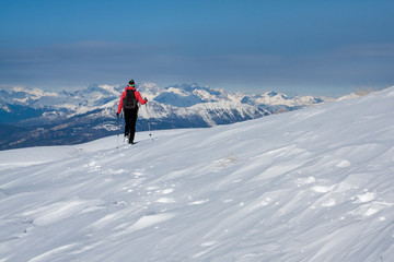 Naklejka na ściany i meble Girl walking alone one the snowed Alps