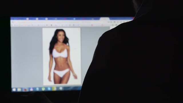 Lustful male looking at sexy women in bikinis on laptop screen, debauchery