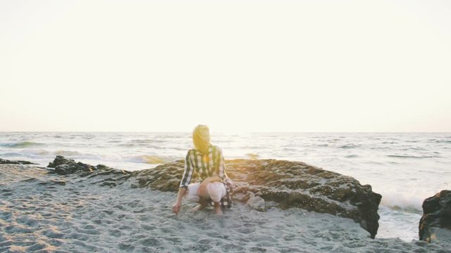 Young female playing with siberian husky dog on the beach at sunrise, slow motion