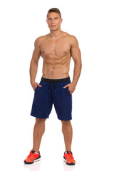 Fototapeta premium Fit Young Man In Shorts Posing With Hands In Pockets