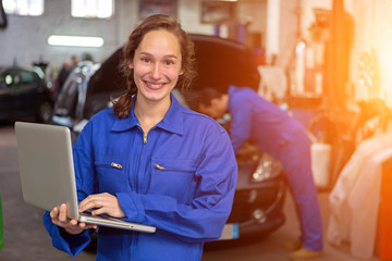 Young attractive woman mechanic working at the garage