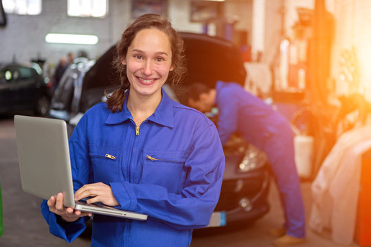 Young attractive woman mechanic working at the garage