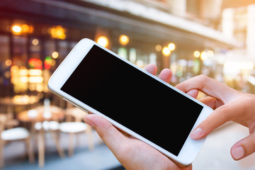 woman hand hold and touch screen smartphone, tablet,cellphone over blurred restaurant background.