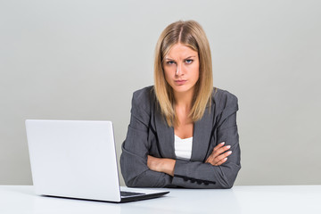 Portrait of very angry businesswoman with laptop sitting at the table.
