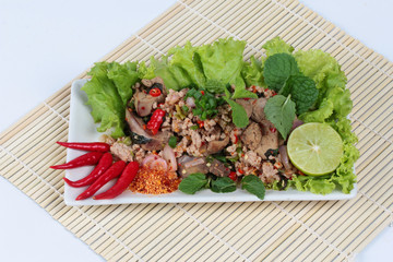 Spicy and sour mixed herb salad with pork and chicken on bamboo and white. Side view.