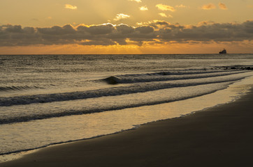 Sea-going vessel near the coast at sunset.