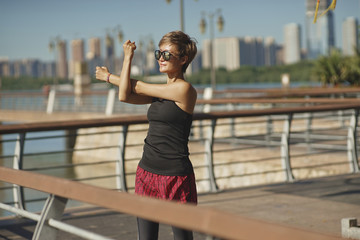 young woman stretching arms after jogging with skyline background