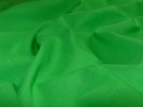 текстура зеленой ткани, насыщенного цвета уложенная в складку    