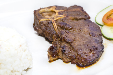 T Bone steak with rice and sauce on a white plate in a restaurant