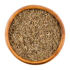 Cumin seeds in a wooden bowl on white background. Dried whole fruits of Cuminum cyminum, used as a spice in cuisine for its distinctive flavour and aroma. Isolated macro photo close up from above.