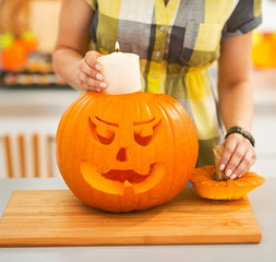 Closeup on woman putting candle inside pumpkin Jack-O-Lantern