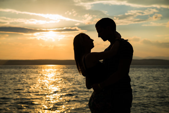 silhouette teenager lovers couple on sunset dusk sky background at the beach:black shadow hand drawn of people hug and kiss people:passion in love concept:warm shine light:decoration,design,valentines