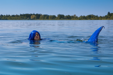 Junge, blauhaarige Meerjungfrau schwimmt 