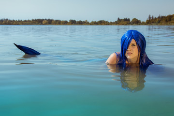 Junge, blauhaarige Meerjungfrau im Wasser