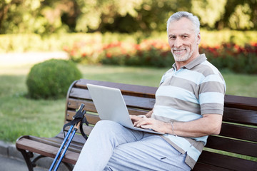 Obraz premium Stylish handsome old man sitting in a park wearing sportswear.