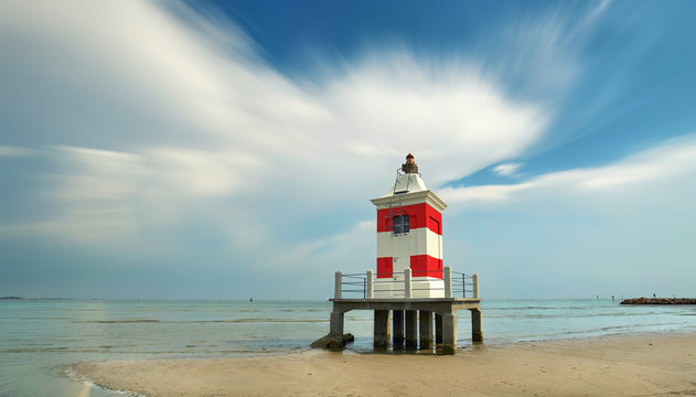 Strand in Italien mit rot wei&szlig;en Leuchtturm