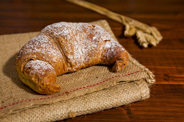 Croissant on a burlap and ears of wheat