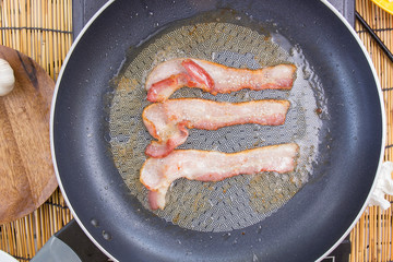 Chef frying bacon in the pan