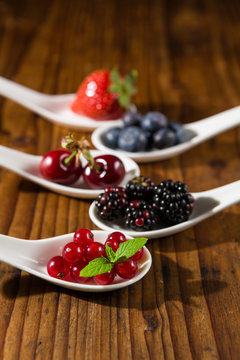 Closeup of collection of wild berries on white spoons