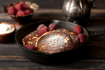  cottage cheese pancakes with raspberries in frying pan. rustic style