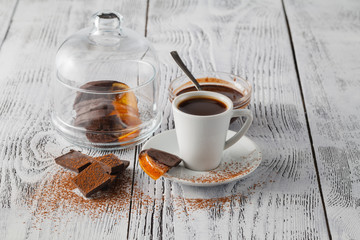 cup of coffee, caramelized orange slices on wooden table