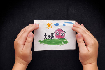 Child protects a drawn house with family