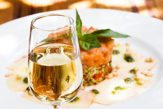 Glass of sherry jerez, pink salmon fish tartar plate background, soft focus photo