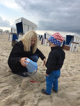Kind baut Sandburg mit Mutter